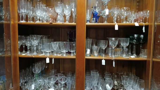 toutes sortes de verres Vitrine en bois contenant divers verres en cristal et en verre, étiquetés à vendre.